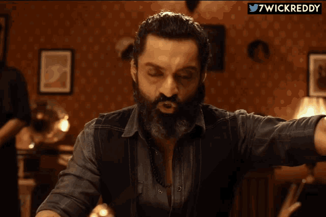 a man with a beard is making a funny face with the hashtag 7wickreddy on the bottom right