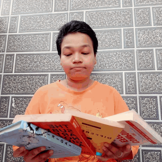 a man in an orange shirt is reading two books one of which is titled economics