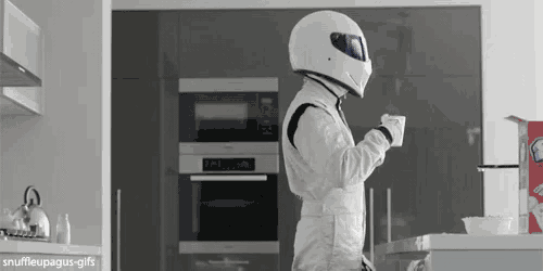 a person wearing a helmet is standing in a kitchen holding a cup of coffee