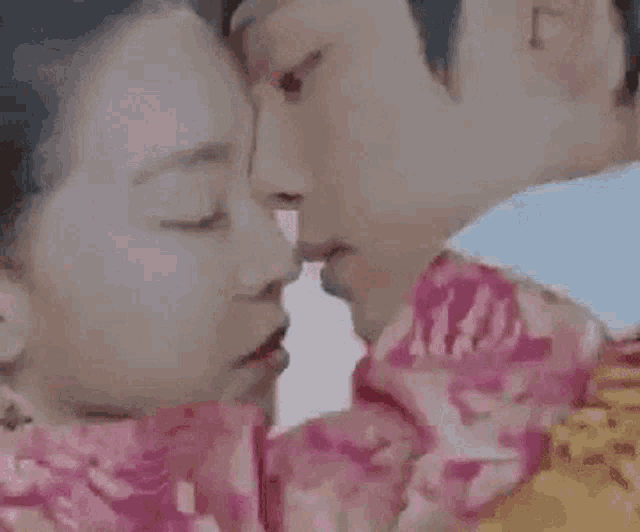 a man and a woman are kissing each other in a close up .