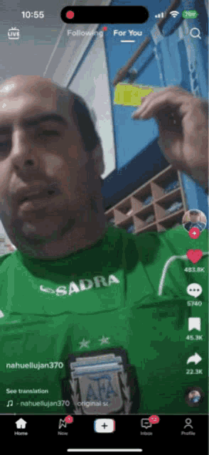 a man wearing a green sadra shirt is talking on a phone