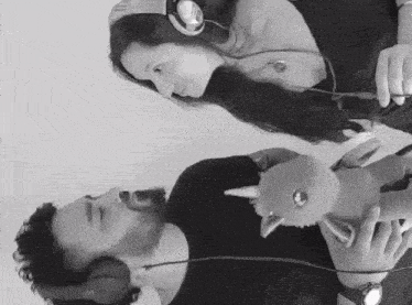 a black and white photo of a man and a woman wearing headphones holding a stuffed animal .