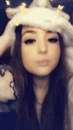 a girl is wearing a unicorn hat and making a face .