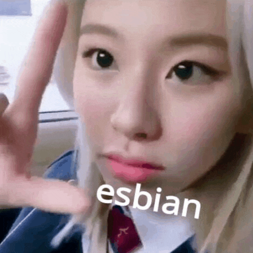 a close up of a woman making a peace sign with her hand and the word esbian on her face .