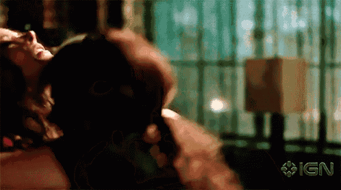 a man is holding a woman 's neck in a dark room with ign written on the bottom right corner .