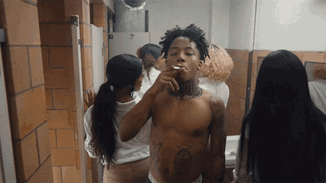 a shirtless man smoking a cigarette in a public restroom