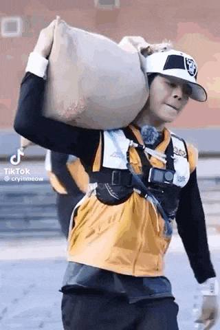 a man in a baseball cap is carrying a large bag on his back .
