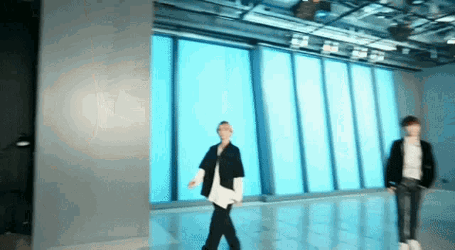 a blurry picture of two people walking in a room with a lot of windows .