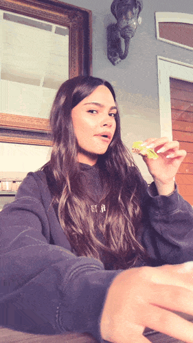 a woman wearing a black sweatshirt with the letter r on it is eating a piece of food