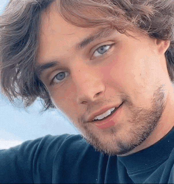 a close up of a man 's face with blue eyes and a beard