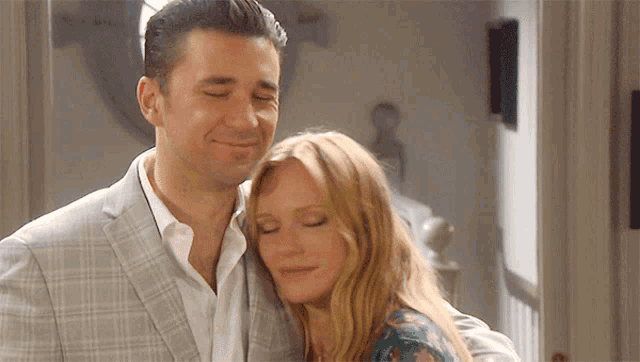 a man in a suit is hugging a woman in a floral shirt