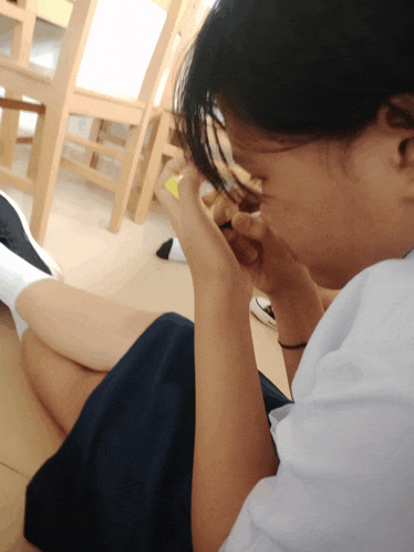 a girl is sitting on the floor with her legs crossed and looking at her phone