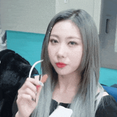 a woman with gray hair and red lipstick is holding a straw in her mouth .