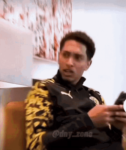 a man is sitting on a couch looking at his phone
