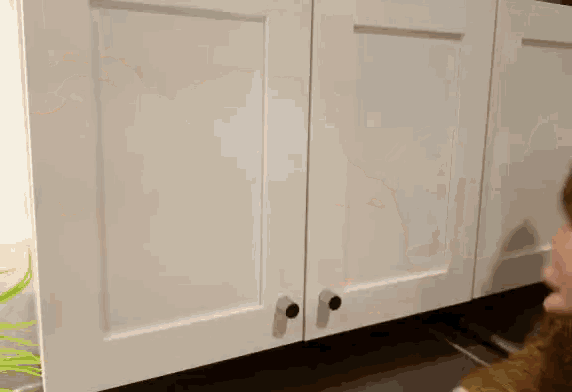 a person is standing in front of a white cabinet with black knobs .