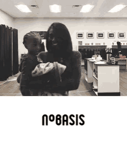 a woman is holding a baby in a room with the word basis on it