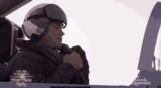 a man in a helmet sits in the cockpit of a plane with the words merry movie week on the bottom right