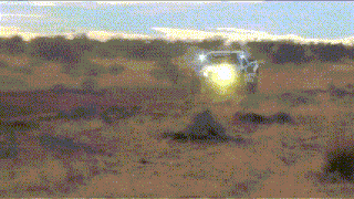 a blurred image of a desert with a car in the distance