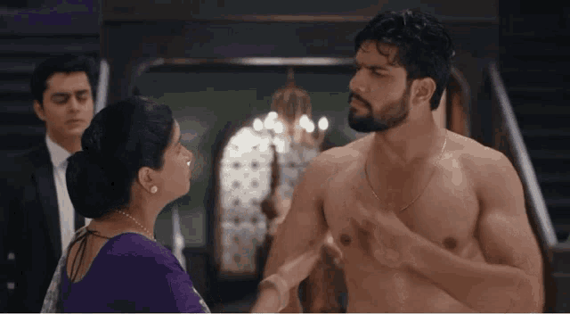 a shirtless man is being held by a woman