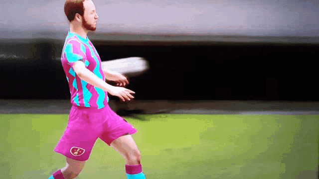 a soccer player wearing a pink and blue jersey with the word fc on the shorts