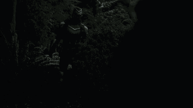 a man in a black and blue suit is walking through the woods at night