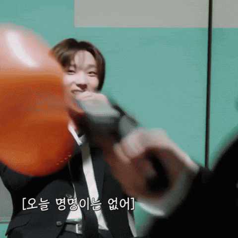 a man in a suit is blowing up an orange balloon with a microphone