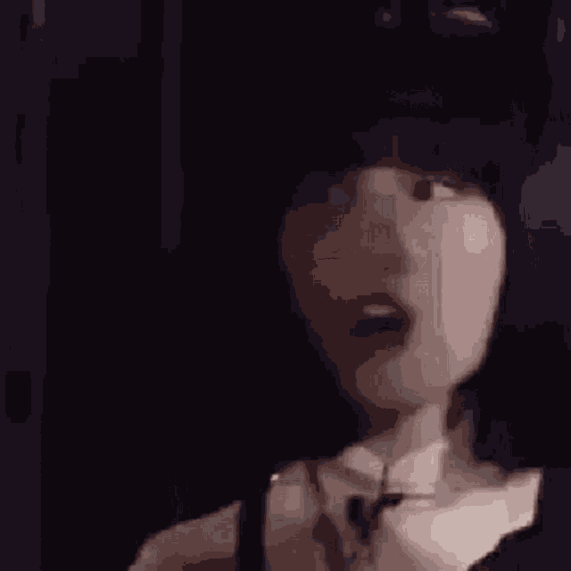 a close up of a woman 's face with a surprised look on her face in a dark room .