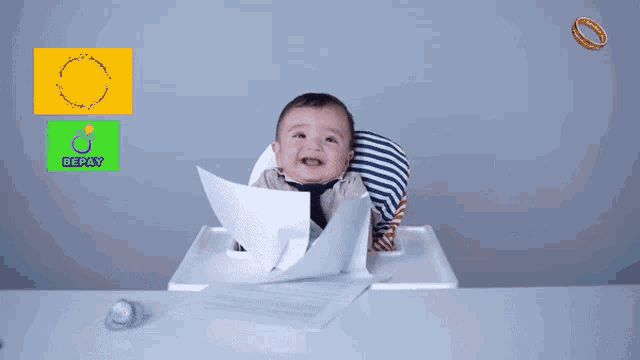 a baby sits in a high chair holding a piece of paper in front of a bepay sign