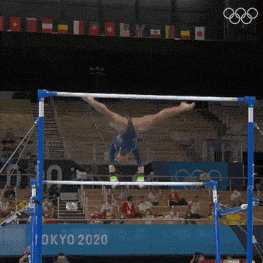 a gymnast is doing a handstand on a parallel bars at tokyo 2020