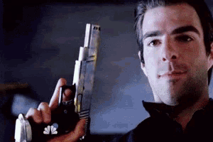 a man is holding a gun and wearing a glove that says nbc