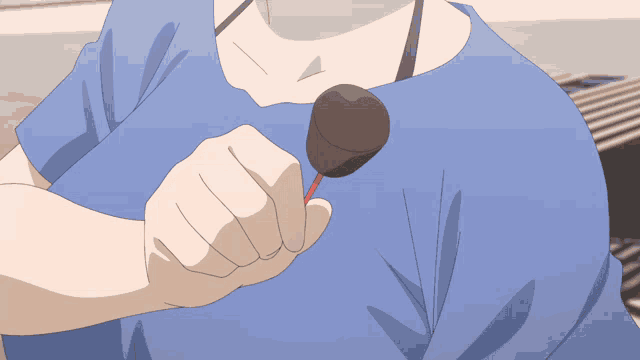 a woman in a blue shirt is holding an ice cream cone on a stick