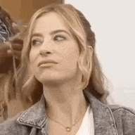 a woman is wearing a denim jacket and a necklace .