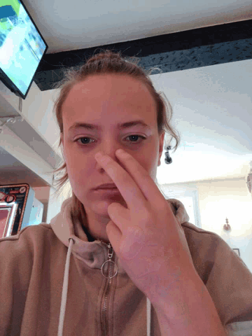 a girl covering her nose with her finger in front of a television