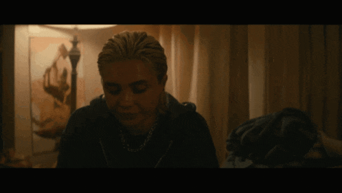 a woman in a dark room with a painting on the wall