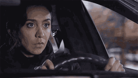 a woman is sitting in the driver 's seat of a car looking out the window