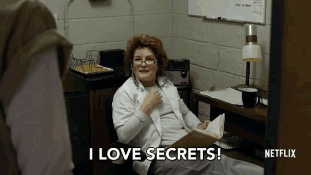 a woman sits at a desk with a book and says i love secrets