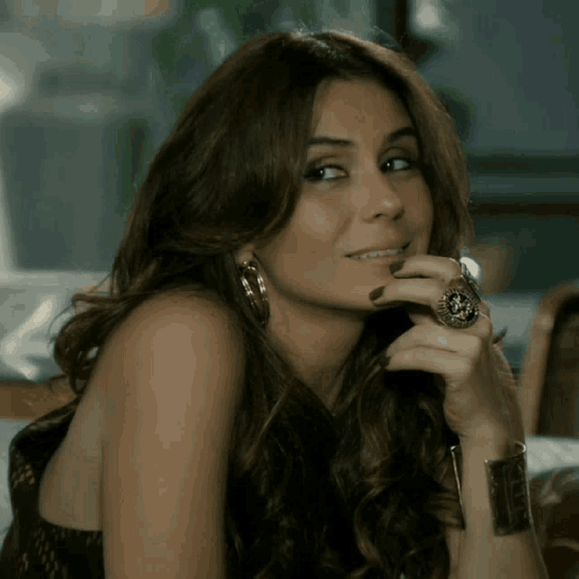 a woman wearing a ring and earrings looks at the camera