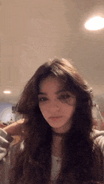 the girl is wearing a choker and a necklace and looking at the camera .