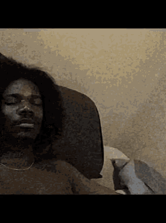 a shirtless man with curly hair is laying on a bed