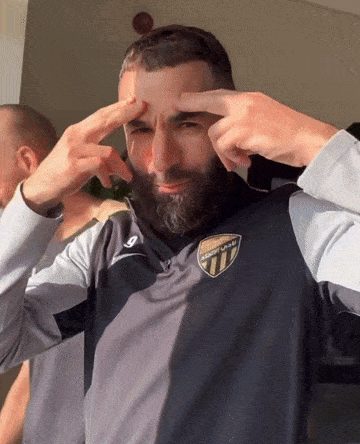 a man with a beard wears a shirt that says atletico madrid