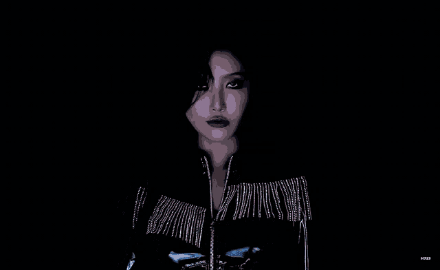 a woman wearing a black jacket with fringe and earrings
