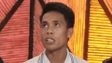 a man in a white shirt is making a funny face in front of a striped wall .