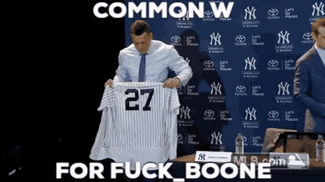 a man is holding a jersey with the number 27 on it