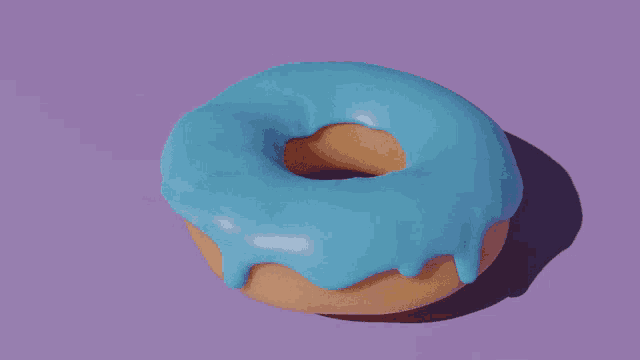 a donut with blue frosting sits on a purple background