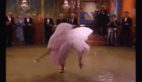 a woman in a pink dress is dancing on a dance floor in front of a group of men in tuxedos .
