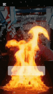 a man in a red shirt stands in front of a fire