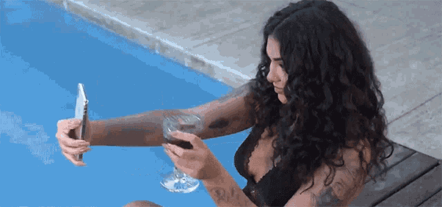 a woman is taking a picture of herself with her phone and a glass of wine