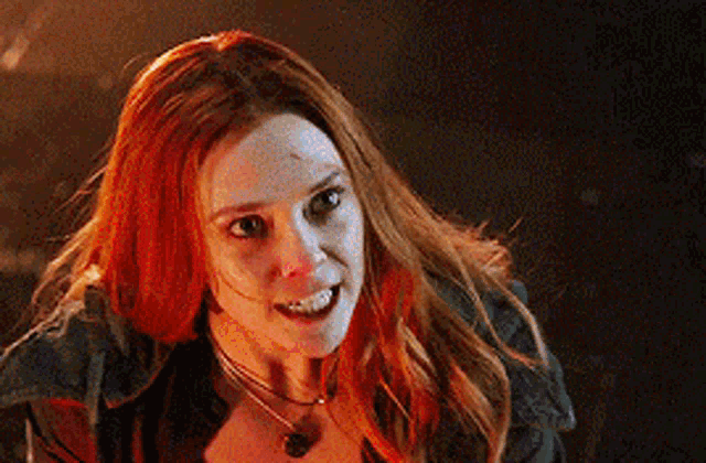 a woman with red hair is wearing a necklace and a jacket .