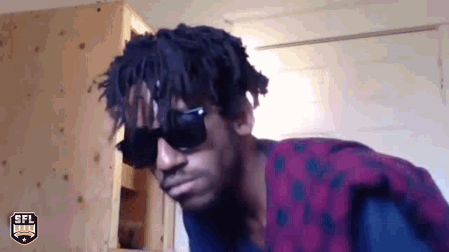 a man wearing sunglasses and a shirt with a sfl logo on it