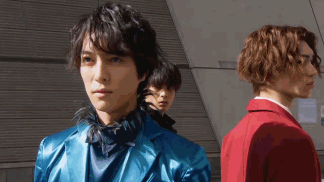 a man in a blue jacket is standing next to another man in a red jacket